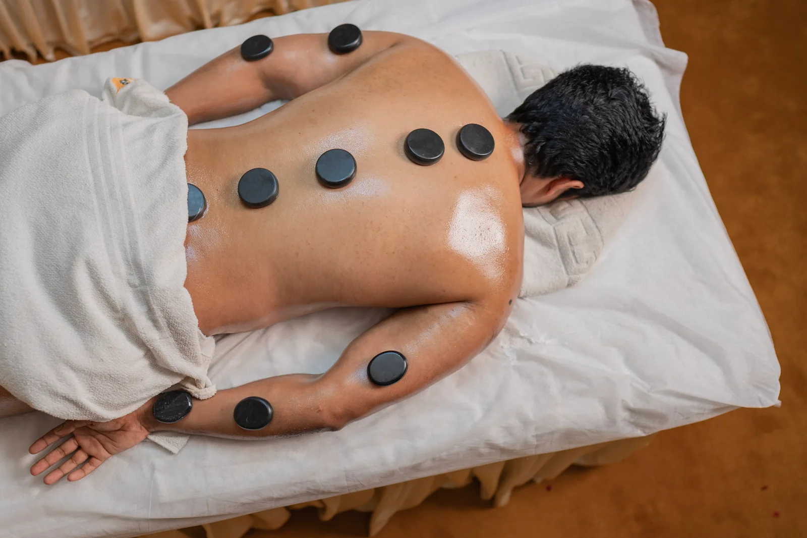 Smiling client lying on massage bed after hot stone therapy