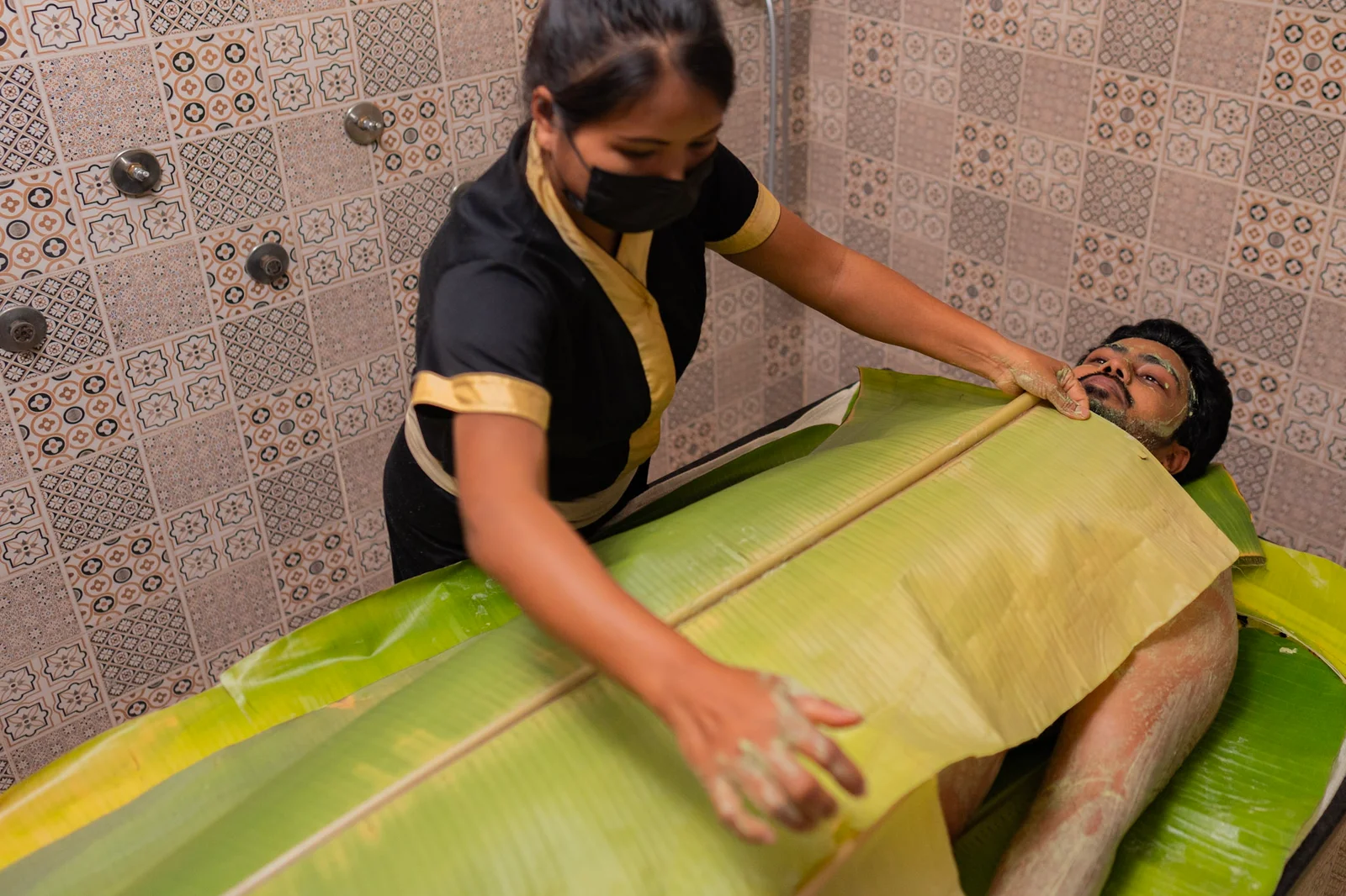 Client wrapped in banana leaf during herbal steam session